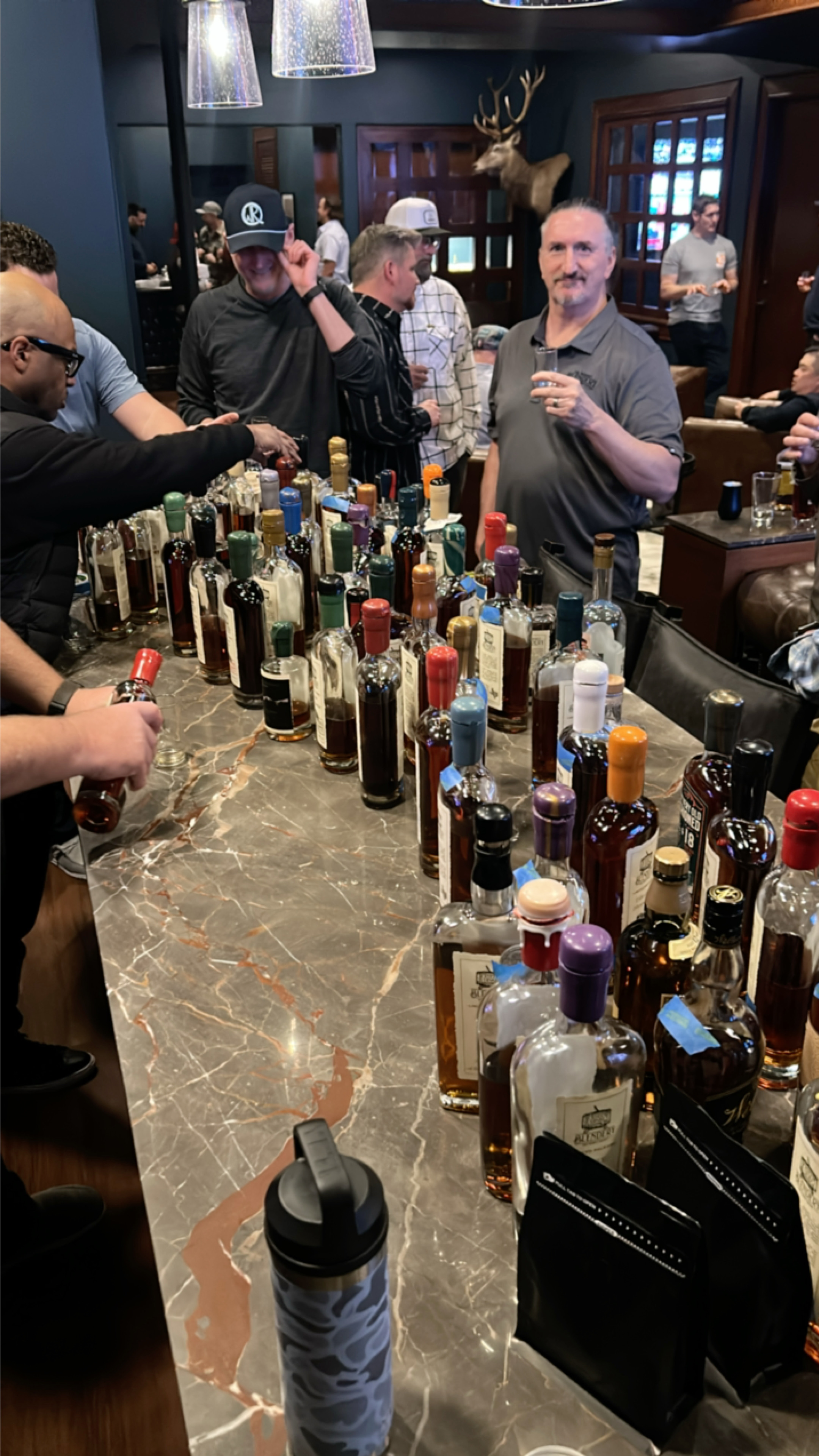 Bar counter lined with bottles and members tasting